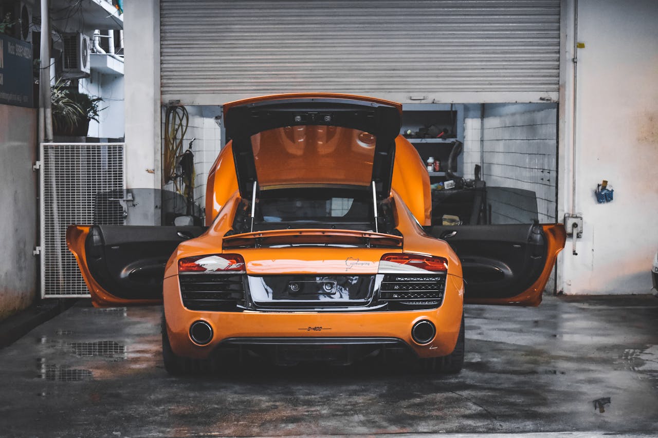 about-img An orange sports car with open doors in a garage, showcasing its luxury design.