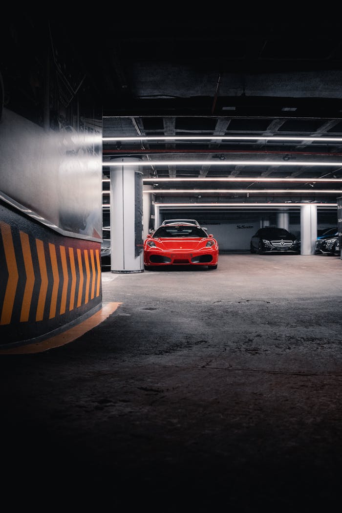 A vibrant red sports car parked in a dimly lit underground garage, showcasing elegance and speed.