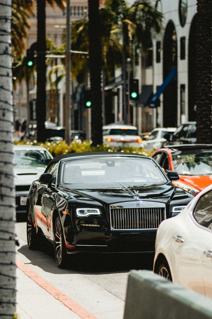 A black luxury convertible car navigating through traffic in Beverly Hills, California.