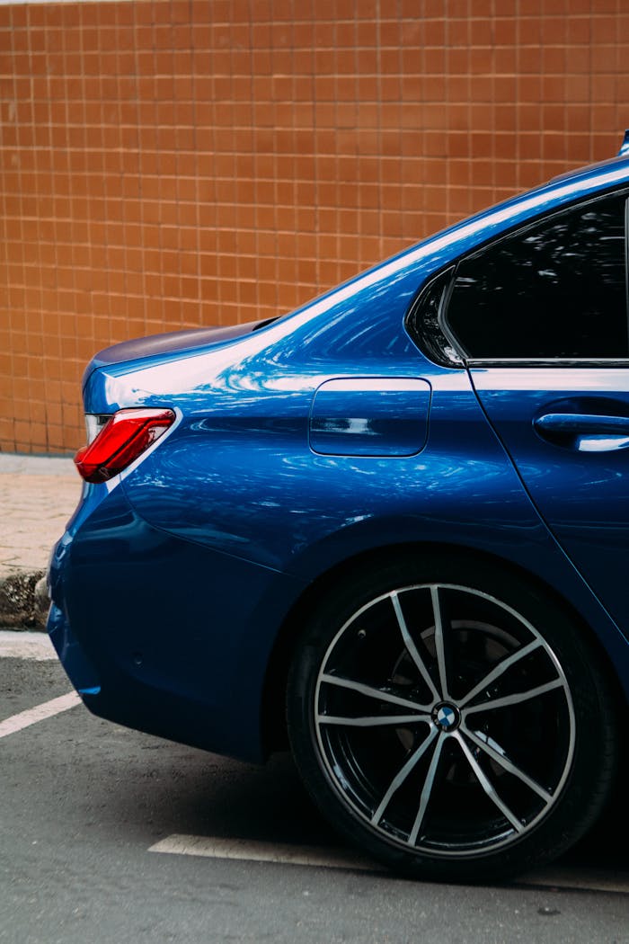 Mastering the First Impression: Your intriguing post title goes here A sleek blue car with alloy wheels parked in a city area with an orange wall.