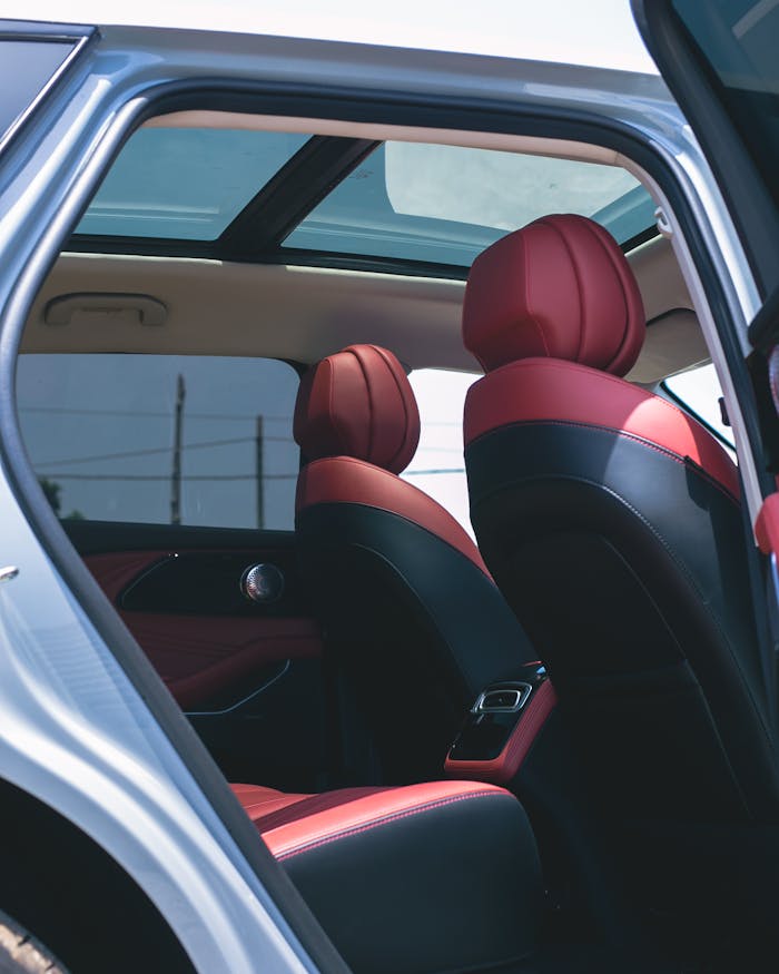 ours-journey Modern car interior featuring sleek red leather seats and panoramic sunroof.