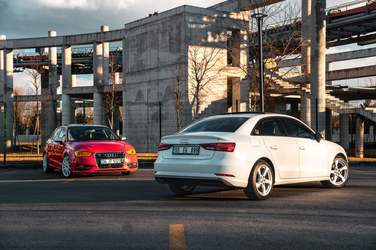 our-experience White and red Audi cars parked against industrial architecture outdoors.
