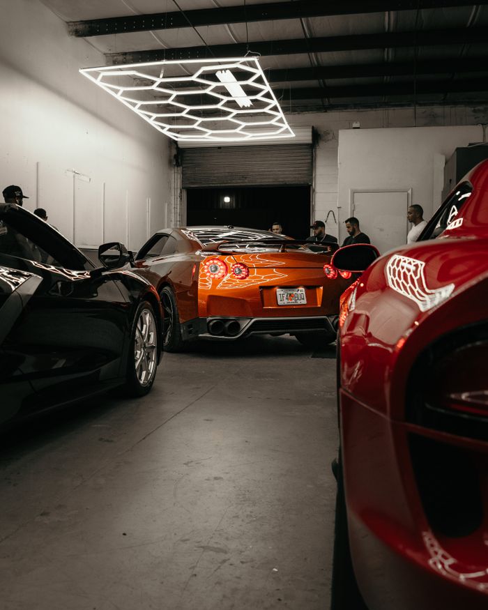Luxury sports cars parked in a modern garage showroom under stylish lighting fixtures.